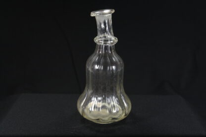 Glasflasche, 18. Jh., leicht gelbstichiges Glas, glockenförmiger Körper spiralförmig gedreht mit Abriß, schräger Hals mit angesetzten Glasknoten. H: 17 cm.