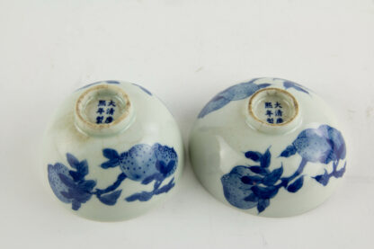2 Schälchen, China, 19. Jh., gemarkt, Kangxi, verziert mit Glückspfirsichen in feiner Blaumalerei, alte Risse und Krakel, sonst unbeschädigt. H: 3,5 cm - 4,5 cm.