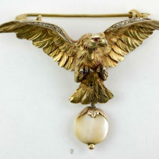 Brosche, um 1900, in Form eines Adlers, Silber vergoldet, Augen mit kleinen Rubinen besetzt, Flügelkanten mit Rosendiamanten, anhängend eine Perlmutscheibe in Rotgold gefasst, sehr feine Ausführung. H: 4 cm, B: 5,7 cm, www.beyreuther.de