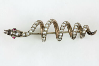Brosche, 19. Jh., Silber, nicht gestempelt, in Form einer Schlange, mit Flussperlen und zwei Rubinen besetzt, sehr dekorativ, Gebrauchsspuren. L: 4,5 cm.