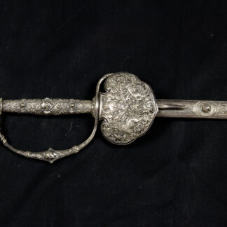 Degen, Dänemark, um 1870, im neoklassischen Stil des Historismus, für Kammerherren, versilbert, Stichblatt mit drei Löwen und bekrönter Wappenkartusche mit der Chiffre Christian des IX verziert, Stahlklinge von Clemen & Jung Solingen, auf der Klinge das Wappen von Hedemann (Degen aus dem Besitz von Marius von Hedemann), Lederscheide (mit Reparaturen), mit Ort- und Mundblech en suit gearbeitet, sehr feine Ausarbeitung, gute Erhaltung, Tragespuren. L: 91 cm.