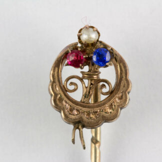 Krawattennadel, Ende 19. Jh., 585er Gold, und Silber, ungemarkt, halbmondförmig, graviert mittig Kleeblatt, mit Rubin, Perle und Saphir besetzt. L: 6 cm. www.beyreuther.de