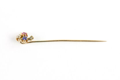 Krawattennadel, um 1900, 585er Gold, ungemarkt, in Form eines Kleebalttes, mit Saphier, Diamant und Rubin besetzt, im Stil kleiner Rosendiamant. L: 5,5 cm.