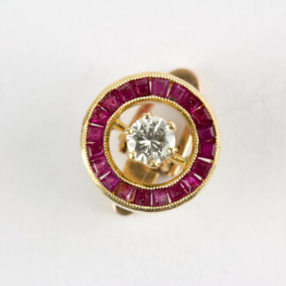 Clip, 20er Jahre, 750er Gold, ungestempelt, in Form eines Ringes, mit Rubin-Karree besetzt, mittig ein Brilliant von 0,20 ct, hochwertige Arbeit, Gebrauchsspuren. D: 11 mm. www.beyreuther.de