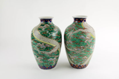 Paar Vasen, Japan, 19./20. Jh., Kutani, umlaufend halbplastisch, geschlungene Drachen auf grünem Grund in Wolken, Gold abgesetzt, Gebrauchsspuren, unbeschädigt. H: 24 cm.