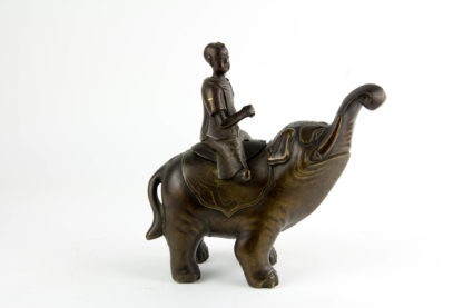 Weihrauchbrenner, China, 19. Jh., Bronze, Junge auf Elefanten sitzend, mit Silber- und Goldeinlagen, ein Arm fehlt. H: 22 cm. Incense burner, China, bronze, boy on an elephant, with silver- and gold inlays, one arm missing. H: 22 cm.