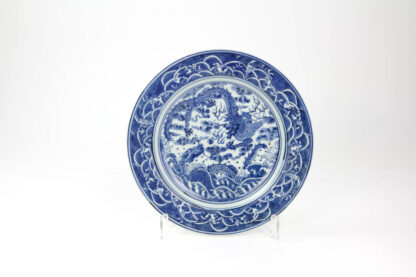 Teller, China, 19./20. Jh., ungemarkt, im Spiegel mit zwei Drachen in Blaumalerei verziert, Fahne mit Wellen bemalt, leichte Gebrauchsspuren, unbeschädigt, D: 23 cm.