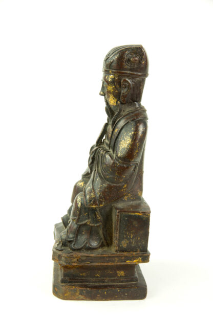 Figur, China, Ming Dynastie, 18. Jh., Eisen, überzogen mit Rotlack, teilweise mit Gold bemalt, Wenchang Wang, Daoistischer Gott der Kunst und Literatur, sitzend, mit Robe, Kopfbedeckung und Hu-Stab in den Händen, gefaltete Hände, auf Sockel, Reste von Goldlack, feine Patina, rückseitig Fünfzeichen-Marke, Gebrauchsspuren. H: 26 cm.