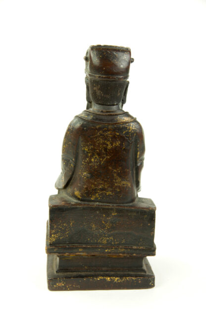 Figur, China, Ming Dynastie, 18. Jh., Eisen, überzogen mit Rotlack, teilweise mit Gold bemalt, Wenchang Wang, Daoistischer Gott der Kunst und Literatur, sitzend, mit Robe, Kopfbedeckung und Hu-Stab in den Händen, gefaltete Hände, auf Sockel, Reste von Goldlack, feine Patina, rückseitig Fünfzeichen-Marke, Gebrauchsspuren. H: 26 cm.