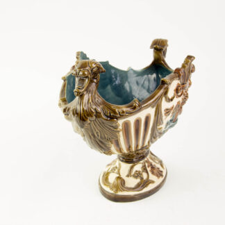 Prunkschale, um 1880, Historismus, Keramik, beigegrundig, erhaben verziert mit Ornamenten und beidseitig Putti unter Akanthusblatt, an den Seiten henkelförmiger Kopfabschluss, Gebrauchsspuren, L: 30 cm, H: 19 cm.