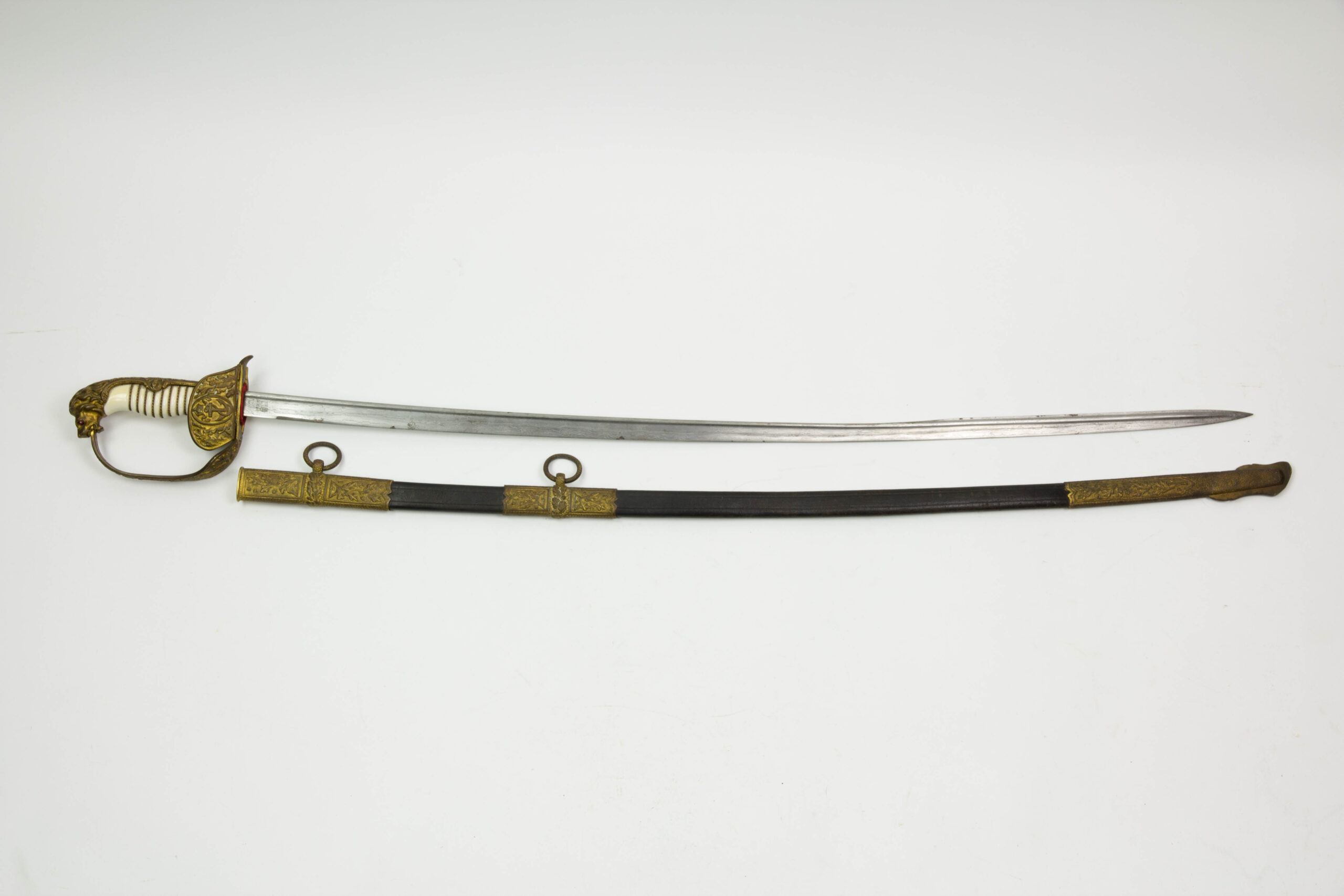 Marine-Säbel, Deutschland, Anf. 20. Jh., vergoldetes Bügelgefäß mit Löwenkopfabschluss, Augen aus zwei Glassteinen in rot (Backbord) und grün (Steuerbord), ausgesuchter Elfeneingriff mit Drahtwicklung, Gefäß mit zwei Klappscharnieren und Eichenlaubverzierungen mit Kaiserkrone, am inneren Scharnier Besitzerbezeichnung "Koch?", Stechrückenklinge von WKC in Streifendamast, Lederscheide mit drei vergoldeten und mit Eichenlaub verzierten Beschlägen, plastisch ausgearbeitete Tragbänder in Form von Eichenlaub, Trageringe verziert, unberührtes Stück mit Patina, hierbei kann es sich um ein Ehrenstück oder eine Luxuswaffe handeln, es gibt äußerst wenig bekannte Stücke dieser Ausführung, Gebrauchsspuren. L: 94 cm.