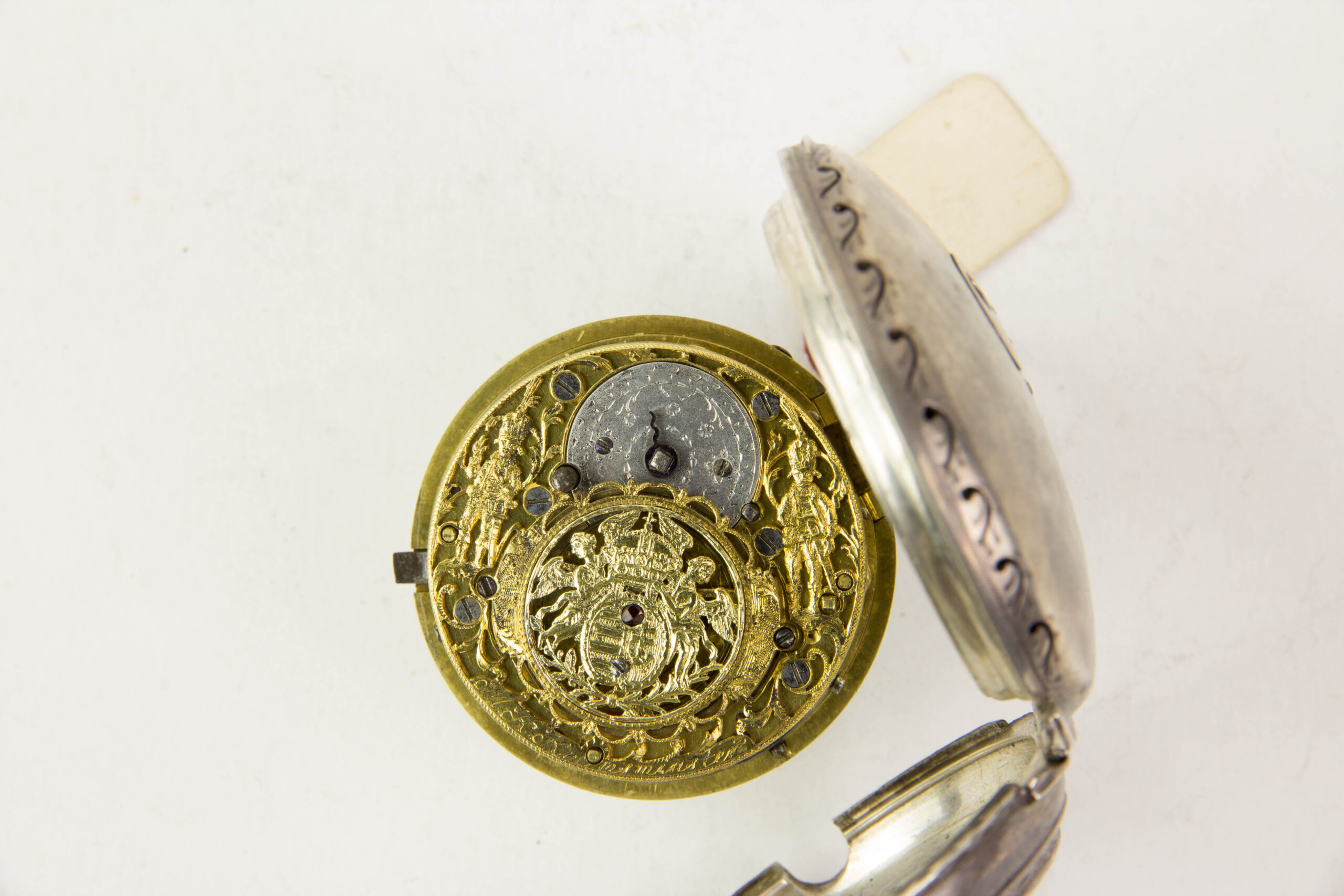 Repetier-Spindel-Taschenuhr, 2. Hälfte 18. Jh., Silber, schlichtes Silbergehäuse mit Ornamenten verziert, Email-Ziffernblatt mit römischen Ziffern, Haarrisse und Chips, durchbrochen gearbeitetes, ausklappbares Uhrwerk, rückseitig vergoldet, und mit zwei plastisch gearbeiteten Husaren verziert, die das ungarische Wappen, das von zwei Engeln gehalten wird flankieren, darunter graviert: M.K. Kremsmünster in Österreich, hoch interessantes Uhrwerk, Uhr läuft an, nicht revidiert. D: 5,5 cm.