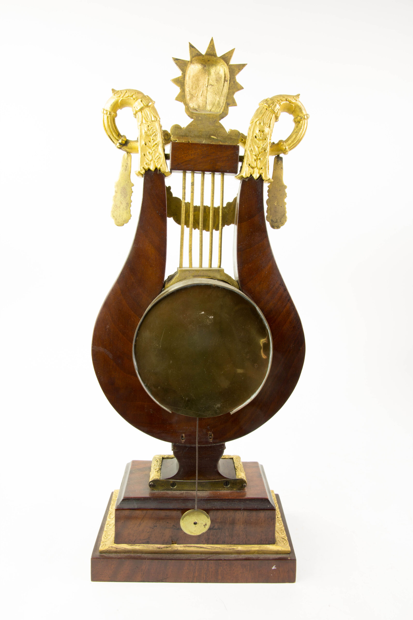 Prunk-Pendule, Anf. 19. Jh., in Form einer Lyra auf Sockel, Mahagoni furniert, reich mit feuervergoldeten Beschlägen verziert, Abschluss David mit Zackenkrone (biblischer König David), flankiert von 2 Schlangen, Email-Ziffernblatt, Fadenaufhängung mit Pendel, ohne Schlagwerk, Schlüssel fehlt, Uhrwerk nicht revidiert, Reparatur oder Reinigung durch Uhrmacher möglich, Gebrauchsspuren. H: 48 cm.