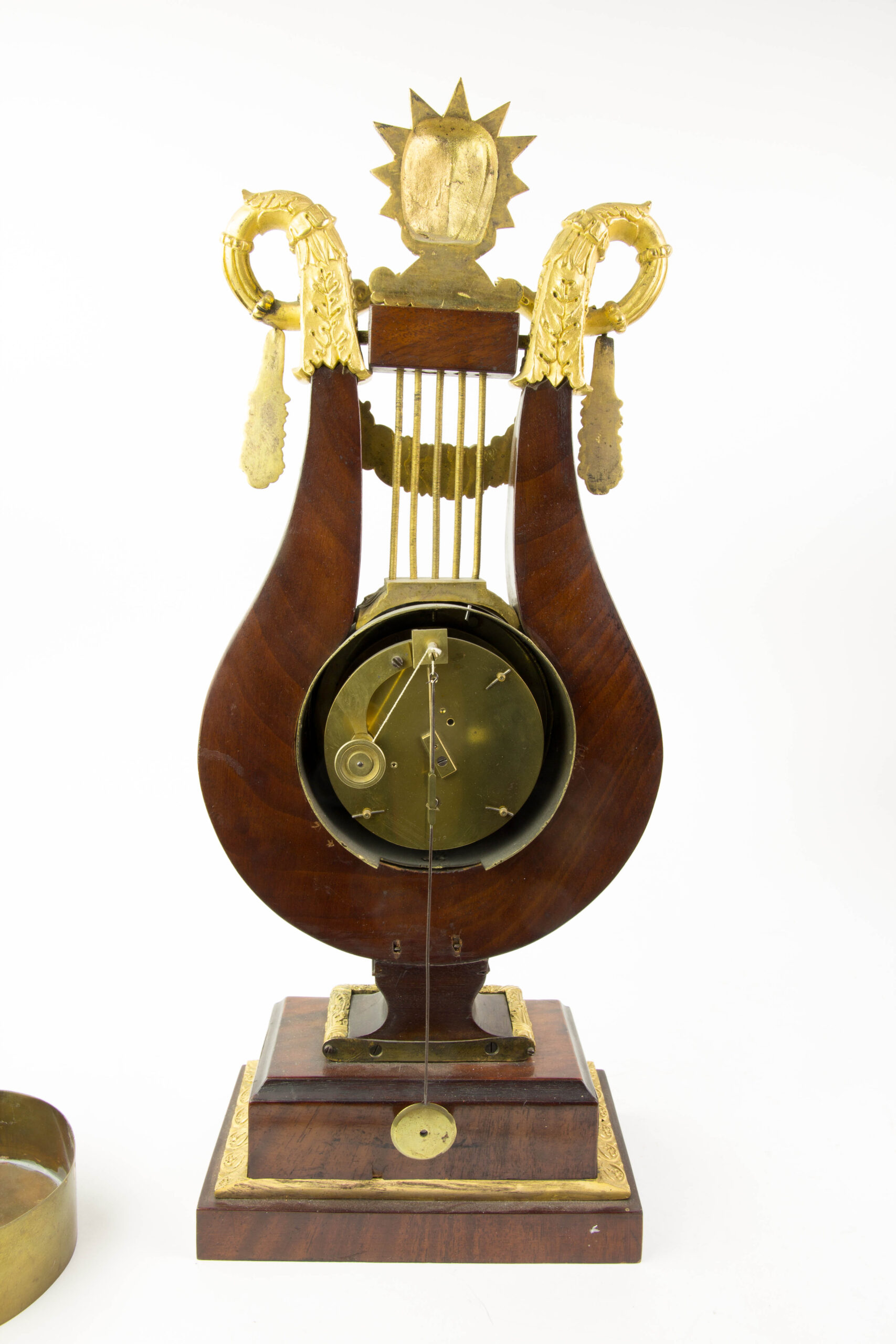 Prunk-Pendule, Anf. 19. Jh., in Form einer Lyra auf Sockel, Mahagoni furniert, reich mit feuervergoldeten Beschlägen verziert, Abschluss David mit Zackenkrone (biblischer König David), flankiert von 2 Schlangen, Email-Ziffernblatt, Fadenaufhängung mit Pendel, ohne Schlagwerk, Schlüssel fehlt, Uhrwerk nicht revidiert, Reparatur oder Reinigung durch Uhrmacher möglich, Gebrauchsspuren. H: 48 cm.