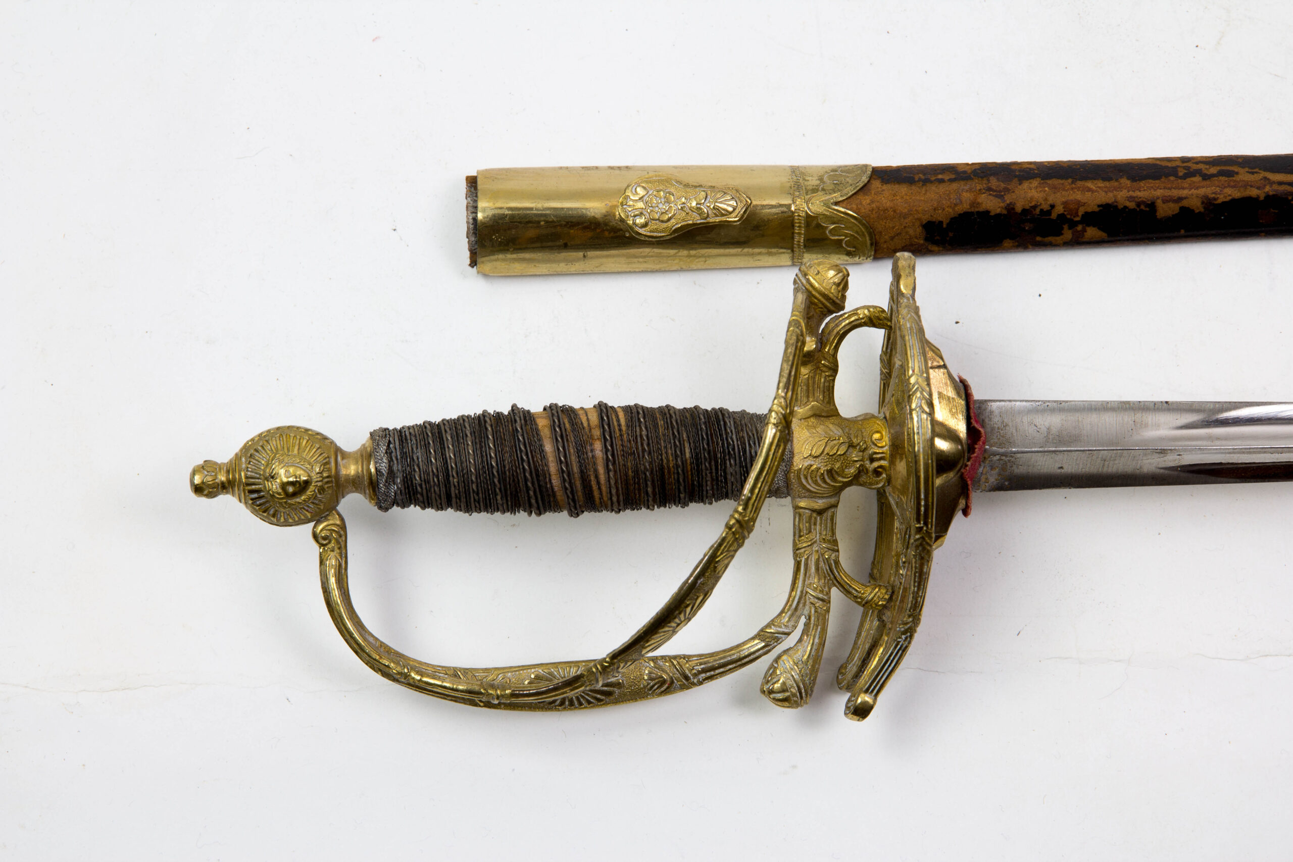 Degen, Frankreich, Modell 1772, 2. Restauration, Gendarmarie de la Garde, vergoldetes Bronzegefäß mit floralen Ornamenten und Girlanden verziert, Silberdrahtwicklung, runder Abschlussknauf mit Sonne und Querbügel, (so nicht bekannt), abklappbares Stichblatt, polierte Dreikantklinge, schwarze Lederscheide (Naht hat sich gelöst, Fehlstellen im Lack), sehr guter Originalzustand, extrem selten, wohl Unikat, vergl. Jean Lhoste Les Épées, Seite 197 und 345. L: 100 cm.