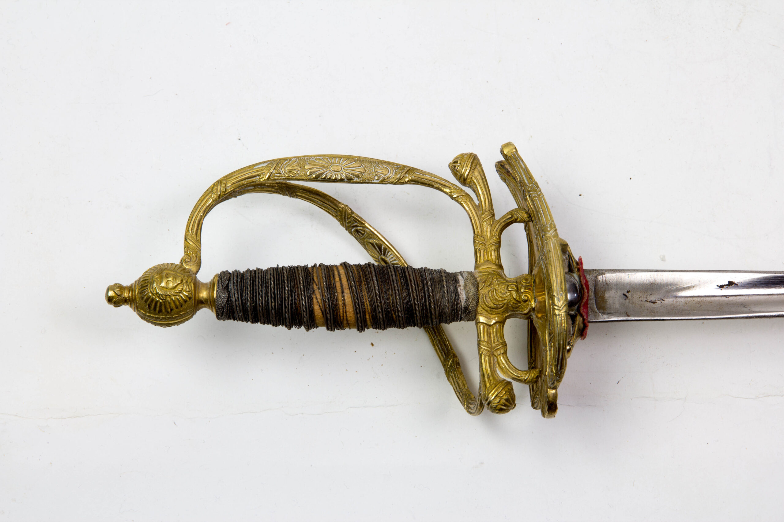 Degen, Frankreich, Modell 1772, 2. Restauration, Gendarmarie de la Garde, vergoldetes Bronzegefäß mit floralen Ornamenten und Girlanden verziert, Silberdrahtwicklung, runder Abschlussknauf mit Sonne und Querbügel, (so nicht bekannt), abklappbares Stichblatt, polierte Dreikantklinge, schwarze Lederscheide (Naht hat sich gelöst, Fehlstellen im Lack), sehr guter Originalzustand, extrem selten, wohl Unikat, vergl. Jean Lhoste Les Épées, Seite 197 und 345. L: 100 cm.