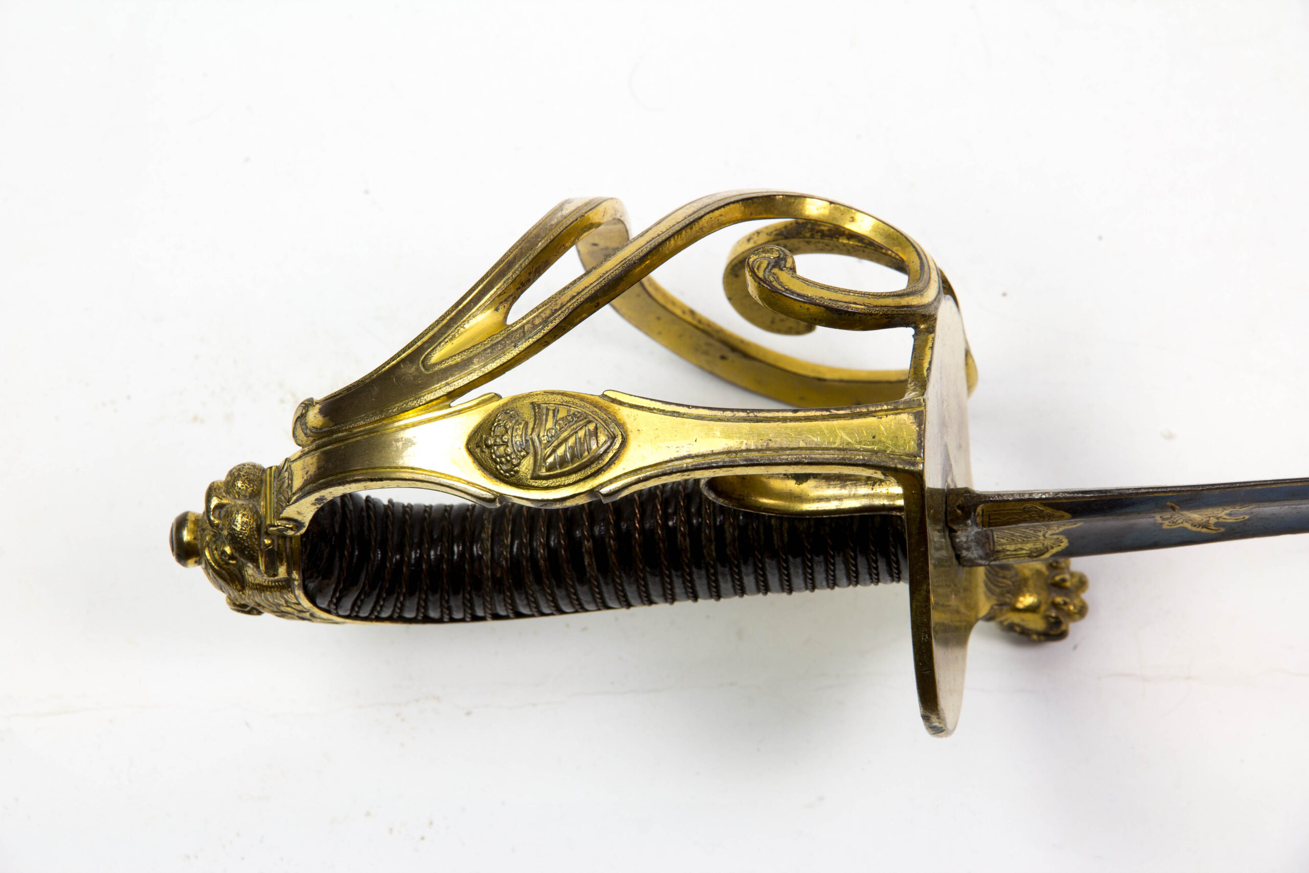 Offizierssäbel, Sachsen, nach 1806, Leibkürassier - Garde, Löwenkopfgefäß mit 3 Nebenbügeln, zwei davon eingerollt, Bronze, ovales Stichblatt in einer Löwentatze endend, Holzgriffstück mit Leber überzogen und Drahtwicklung, sächsisches Wappen auf dem Hauptbügel, Rückenklinge mit Hohlschliff, im ersten Drittel gebläut, vergoldet und mit Ornamenten und Kriegsgirlanden verziert, dazu Messingscheide mit zwei plastischen Löwenköpfen und Trageringen, Reste einer Vergoldung, absolut unberührtes Stück mit schöner Patina und guter Erhaltung, das Regiment wurde 1822 in Russland komplett aufgerieben, einzigartiges Stück. L: 101 cm.